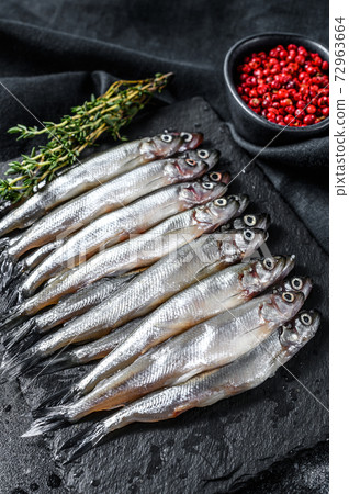 Raw small fish anchovies with pepper and thyme. Black background. Top view 72963664