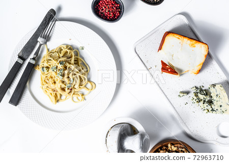 Spaghetti paste with cream blue cheese sauce and walnuts. Italian Home made food. Concept for a tasty, vegetarian dish. White background. Top view 72963710