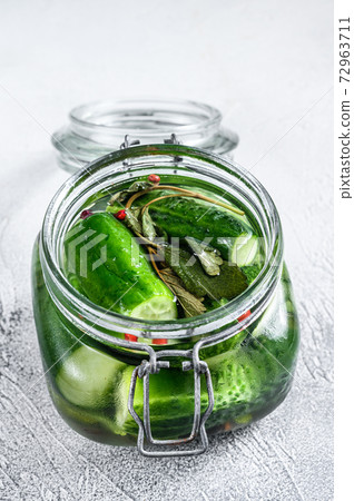 Green pickle cucumbers in a glass jar. Natural product. White background. Top view 72963711