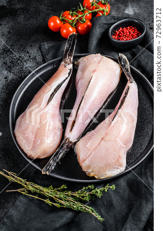 Separate fresh monkfish without head and skin. Black background. Top view 72963712