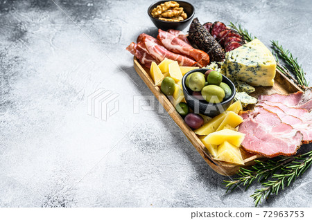 Antipasto platter with ham, prosciutto, salami, blue cheese, mozzarella and olives. Gray background. Top view. Space for text Antipasto platter with ham, prosciutto, salami, blue cheese, mozzarella and olives. Gray background. Top view. Space for text 72963753
