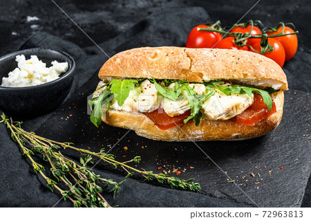 Ciabatta sandwich with fresh goat cheese, pear marmalade and arugula. Black background. Top view 72963813