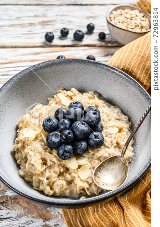 Breakfast oatmeal with blueberries and almonds. White wooden background. Top view 72963814