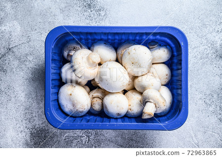 Fresh champignons in plastic packaging. Gray background. Top view Fresh champignons in plastic packaging. Gray background. Top view 72963865