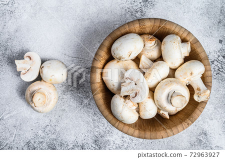 Raw mini mushroom champignon in a bamboo bowl. Gray background. Top view. Space for text 72963927