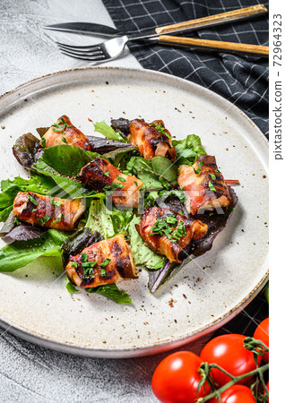 stuffed chicken breasts, fillets rolled in bacon with green salad. Gray background. Top view stuffed chicken breasts, fillets rolled in bacon with green salad. Gray background. Top view 72964323