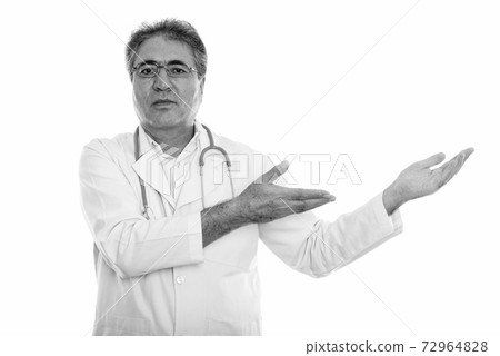Studio shot of senior Persian man doctor showing something 72964828
