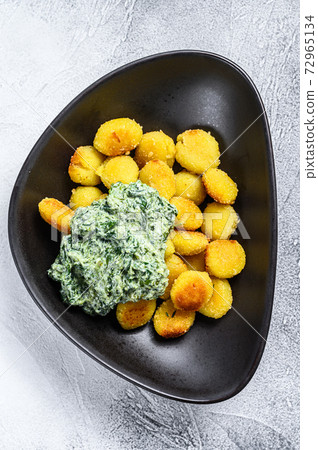 Fried gnocchi potato pasta with spinach. White 72965134