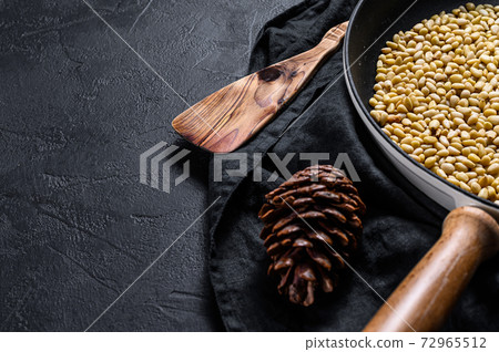Roasted pine nuts in a frying pan. Black 72965512