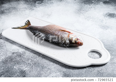 crucian carp on a white chopping Board. Gray crucian carp on a white chopping Board. Gray 72965521