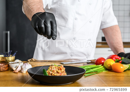 The chef in black gloves prepares tartare from 72965899