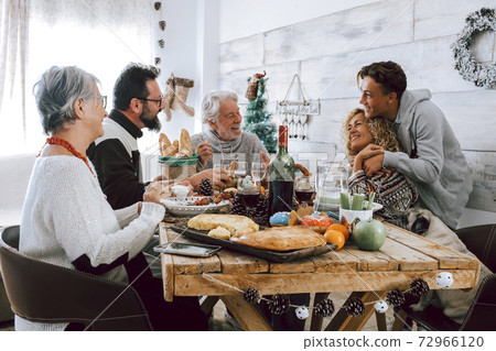 Family enjoy together christmas lunch at home - caucasian people have fun in friendship celebrating holidays and eve - white home and wooden style table Family enjoy together christmas lunch at home - caucasian people have fun in friendship celebrating holidays and eve - white home and wooden style table 72966120
