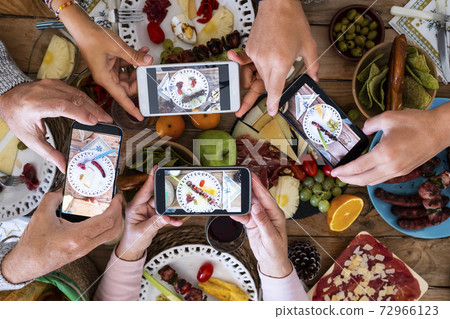People eating together taking food picture with smartphone to share on social media - concept of celebration - wooden table and mixed food in background People eating together taking food picture with smartphone to share on social media - concept of celebration - wooden table and mixed food in background 72966123