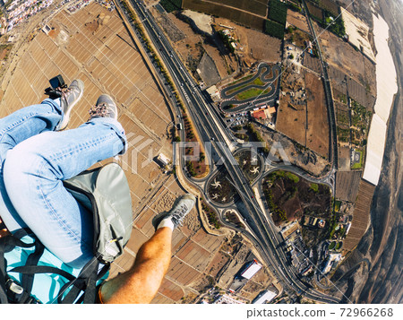Air view of people couple doing paraglyde adrenaline experience - pilot and passenger paraglyiding over the city - outdoor excursion leisure activity 72966268