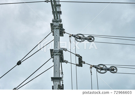 Overhead contact wires of electrified railway tracks against a gloomy sky 72966603