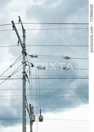 Overhead contact wires of electrified railway tracks against a gloomy sky 72966606