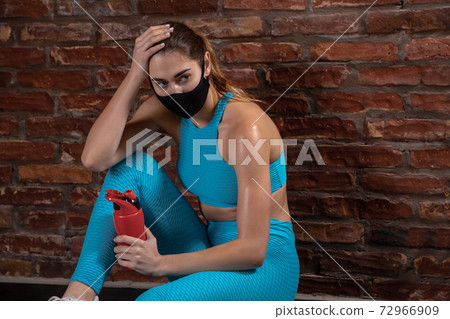 Professional female athlete training on brick wall background wearing face mask. Sport during quarantine Professional female athlete training on brick wall background wearing face mask. Sport during quarantine 72966909