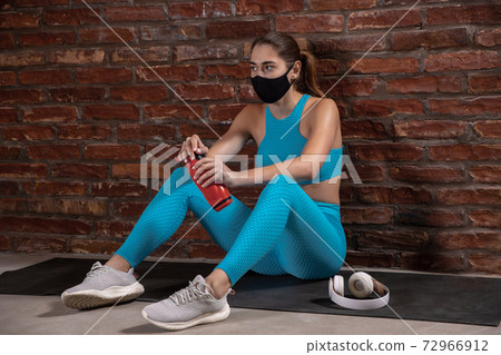 Professional female athlete training on brick wall background wearing face mask. Sport during quarantine Professional female athlete training on brick wall background wearing face mask. Sport during quarantine 72966912