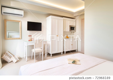 White elegant interior of small studio apartment room with classic style design wooden panel furniture in modern hotel flat. 72968189