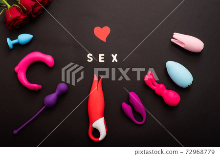 The inscription sex is a heart of roses and a collection of vibrators on a black background. Sex toys of various shapes. Assortment of sex shop 72968779