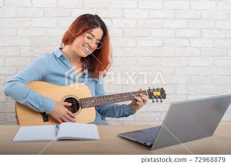 Beautiful caucasian woman is playing the guitar live. Online music training 72968879