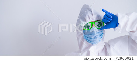 A woman in a protective suit and mask and glasses for st patrick's day gestures booze. A traditional Irish holiday. Widescreen. 72969021