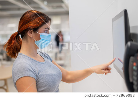 The new norm after the coronavirus epidemic is a woman looking for information with a digital touch screen in a store The new norm after the coronavirus epidemic is a woman looking for information with a digital touch screen in a store 72969098