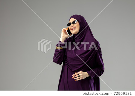 Beautiful arab woman posing in stylish hijab isolated on studio background. Fashion concept Beautiful arab woman posing in stylish hijab isolated on studio background. Fashion concept 72969181