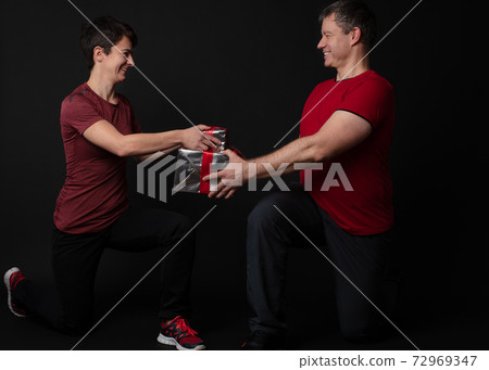 Personal Trainer couple handing a gift box 72969347
