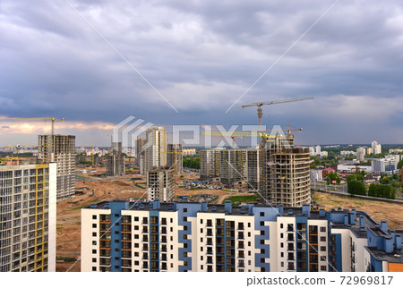 Aerial view on the large construction site with tower cranes and builders in action. Aerial view on the large construction site with tower cranes and builders in action. 72969817