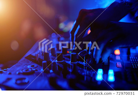 Hand of a DJ girl on the background of a music controller mixer. Hand of a DJ girl on the background of a music controller mixer. 72970031