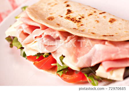 Traditional Italian piadina with ham, cheese, tomato and salad. 72970685