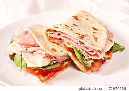 Traditional Italian piadina with ham, cheese, tomato and salad. 72970686