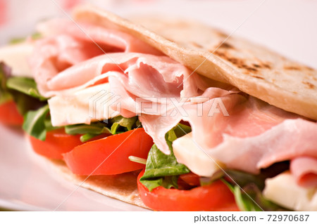 Traditional Italian piadina with ham, cheese, tomato and salad. 72970687