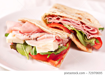 Traditional Italian piadina with ham, cheese, tomato and salad. 72970695