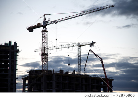 Silhouettes of tower cranes in action on night sky background.  72970906