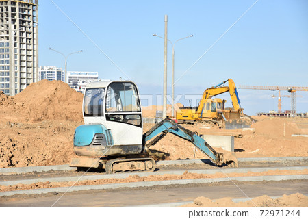 Mini excavator dig a trench to lay cables concrete curbs at construction site. Mini excavator dig a trench to lay cables concrete curbs at construction site. 72971244