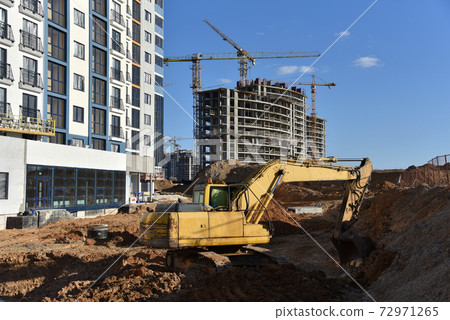 Excavator on earthworks for laying heating pipes and stormwater in trench. Excavator on earthworks for laying heating pipes and stormwater in trench. 72971265
