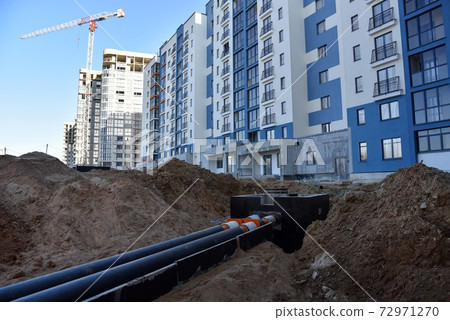 Laying heating pipes in a trench at construction site. Laying heating pipes in a trench at construction site. 72971270