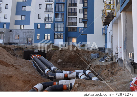 Laying heating pipes in a trench at construction site. Laying heating pipes in a trench at construction site. 72971272