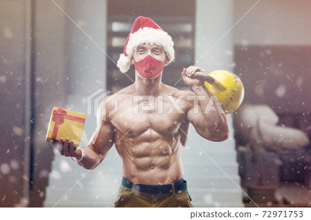 Fitness man in Santa Claus hat costume in gym Fitness man in Santa Claus hat costume in gym 72971753