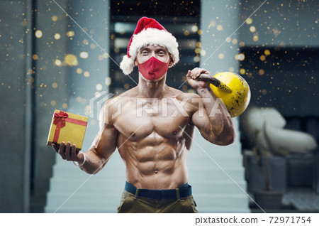 Fitness man in Santa Claus hat costume in gym 72971754
