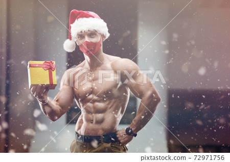 Fitness man in Santa Claus hat costume in gym 72971756