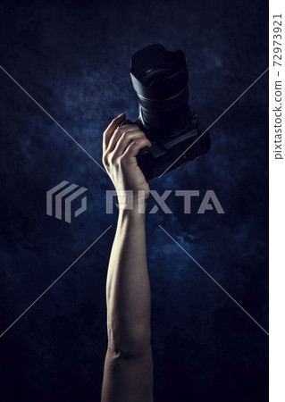 Male hand lifting a single-lens reflex camera 72973921