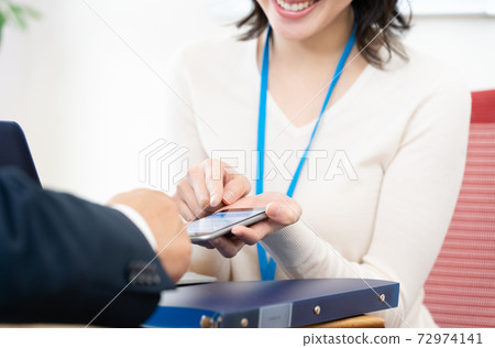 A woman having a meeting while looking at her smartphone 72974141