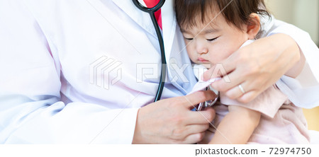 Young female doctor embraced and examined by a sleepy-faced baby banner size 72974750