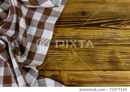 Brown folded checkered napkin on rustic wooden kitchen table. Top view, copy space 72977149