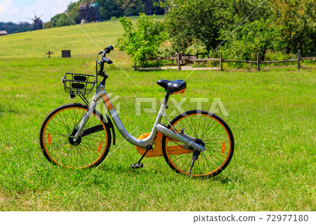 Modern bicycle parked on a green lawn in rural area 72977180