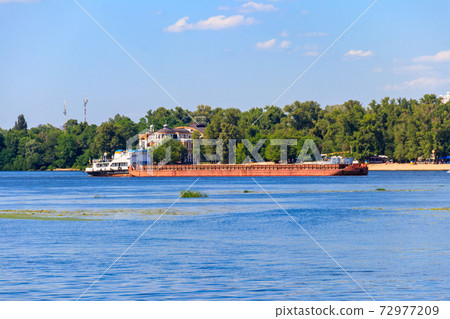 Heavy long barge sailing on the Dnieper river in Kiev, Ukraine Heavy long barge sailing on the Dnieper river in Kiev, Ukraine 72977209