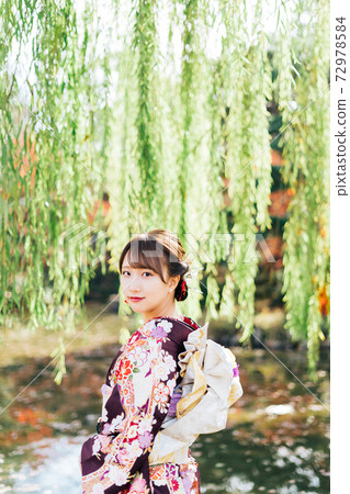 一個穿著和服（袖）站在柳樹下的女人 72978584